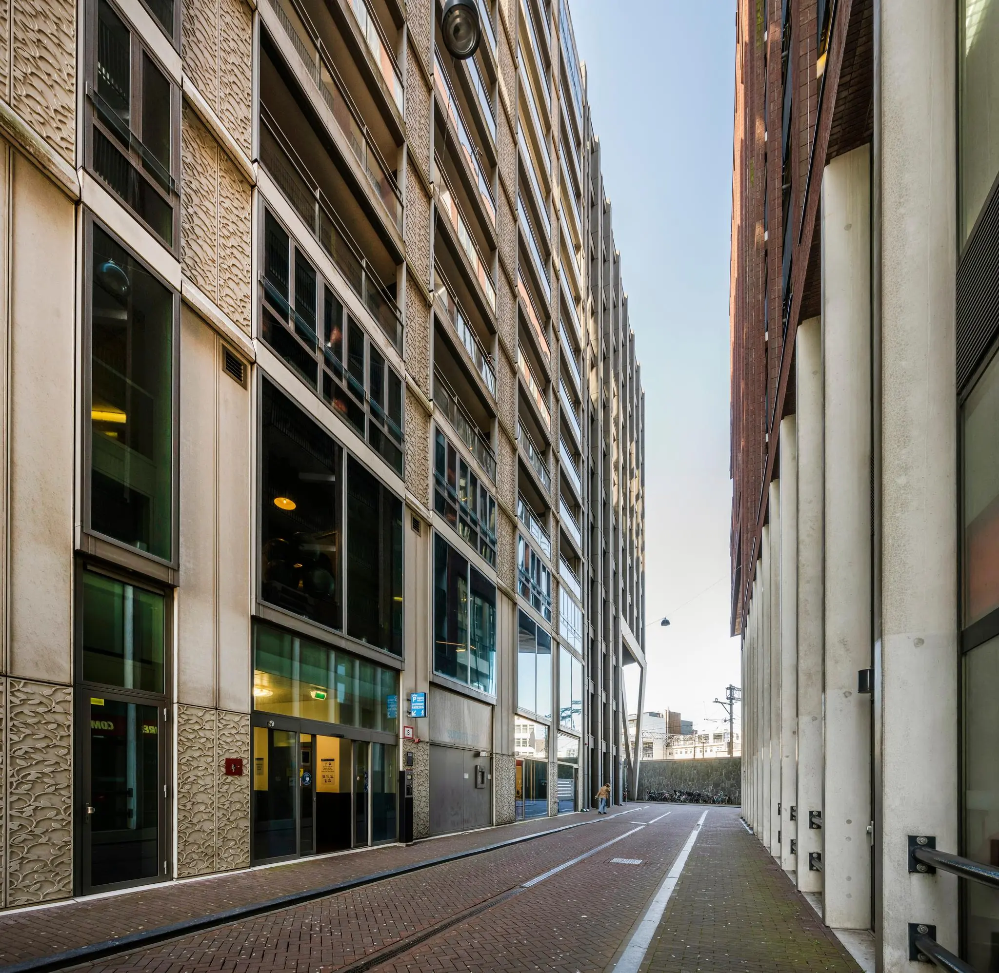 Smalle straat tussen moderne hoge gebouwen aan de Harry Banninkstraat in een stedelijke omgeving.